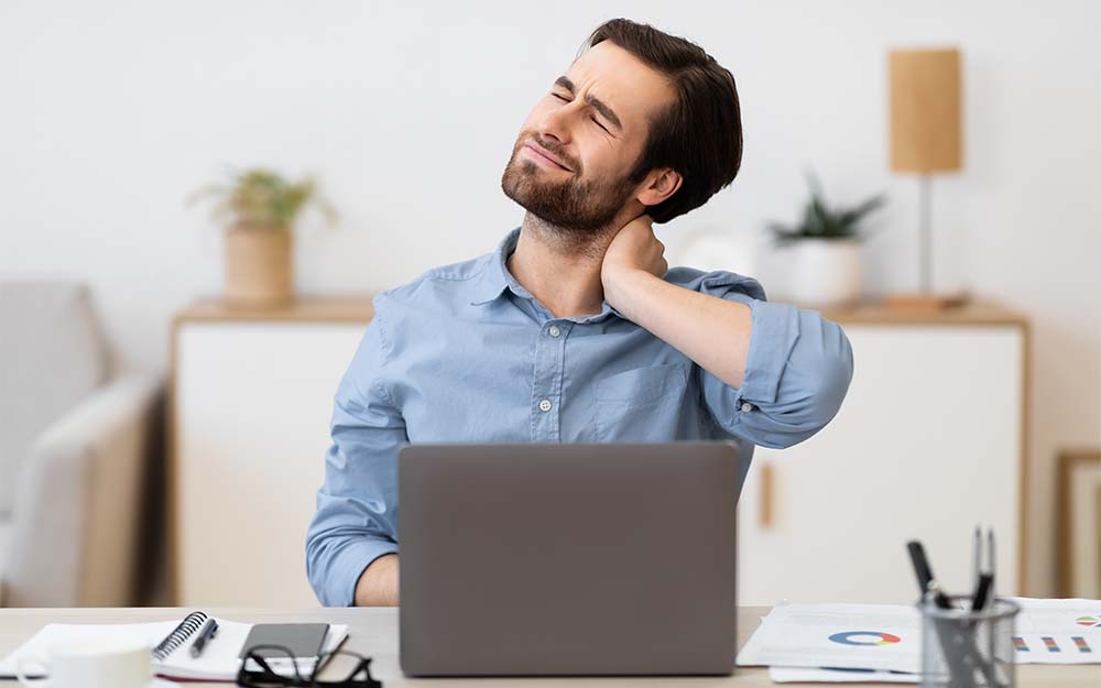 man neck pain working on laptop computer