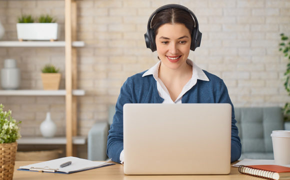 young woman working from home with laptop and headset